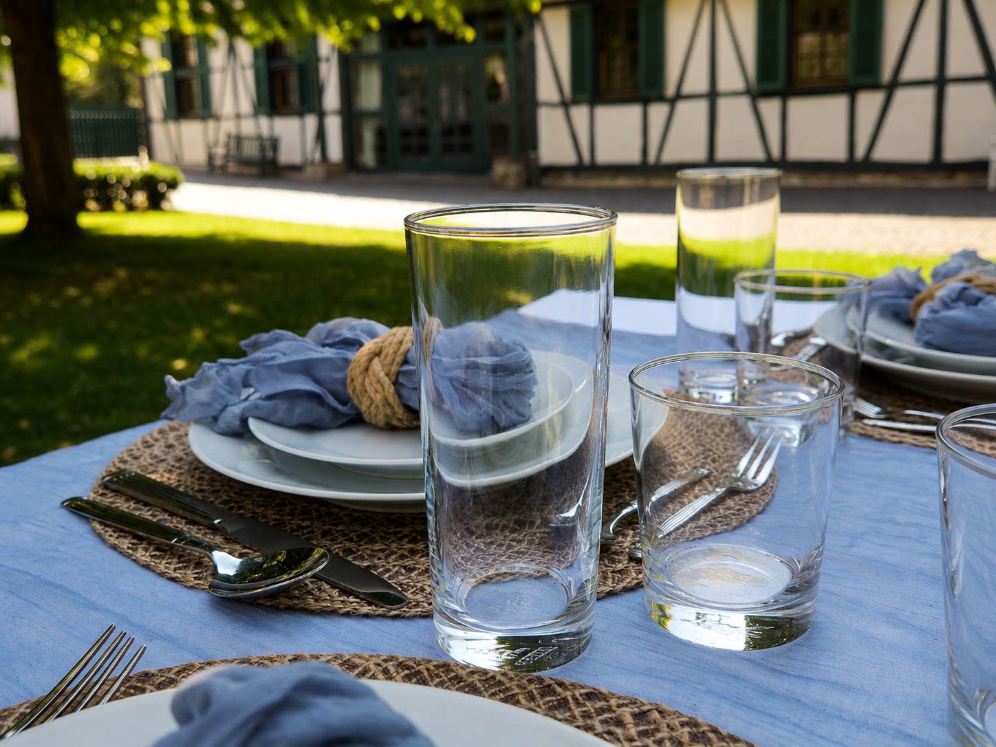Festlich gedeckter Tisch mit klaren Trinkgläsern, weißen Tellern und Tischdekoration