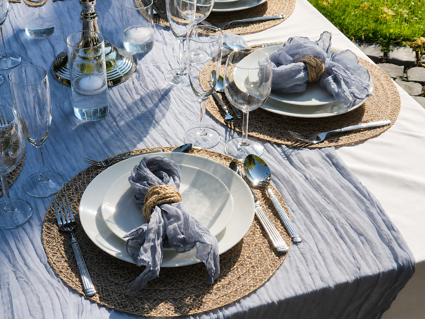  Detailansicht einer Tischdekoration mit dunstblauem Läufer, Stoffservietten, Jute-Platzsets und Serviettenringen